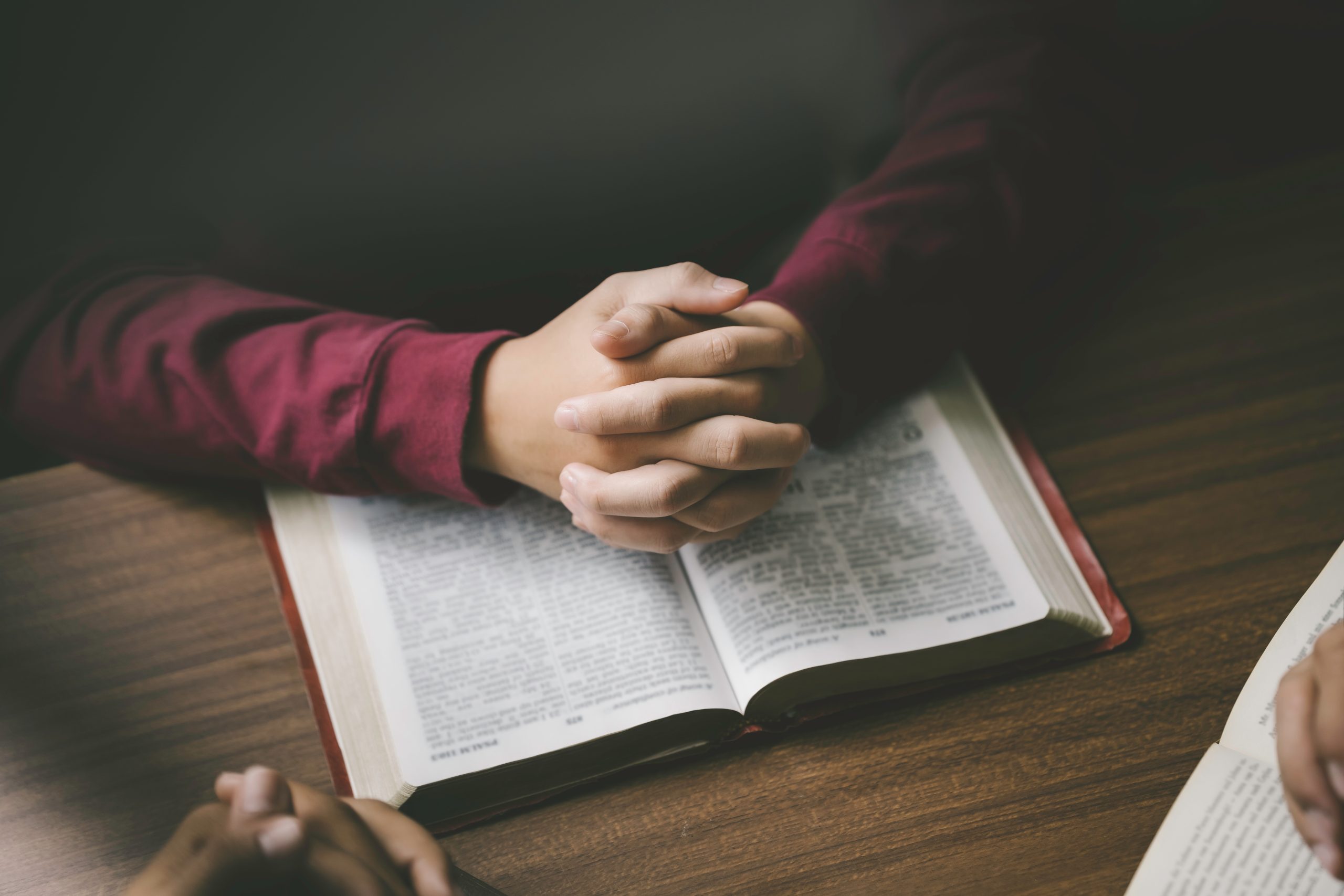 Christian group or family prayer together with a holy bible on a wooden table in church for worship to god in the morning. people pray with faith, Spirituality, and religion concept